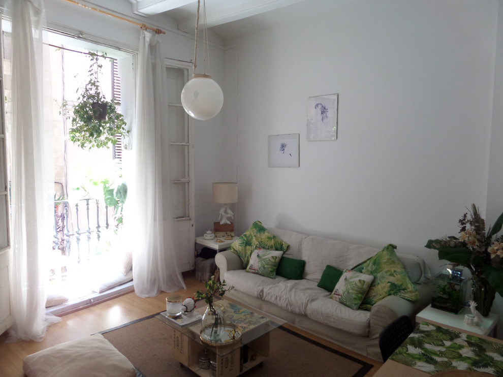 Ejemplo de sala de estar abierta tropical pequeña sin chimenea y televisor con paredes blancas y suelo de madera en tonos medios