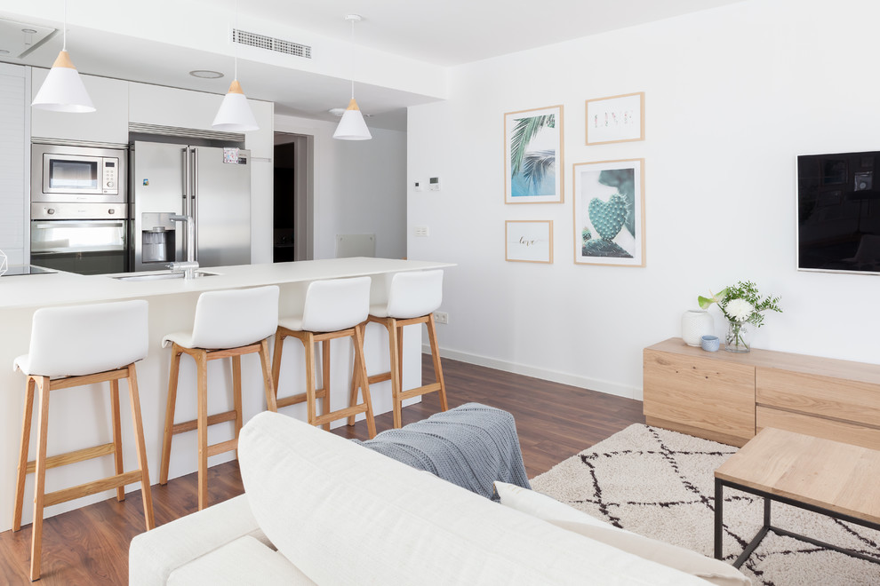 Diseño de sala de estar abierta marinera de tamaño medio con paredes blancas, suelo de madera oscura, televisor colgado en la pared y suelo marrón