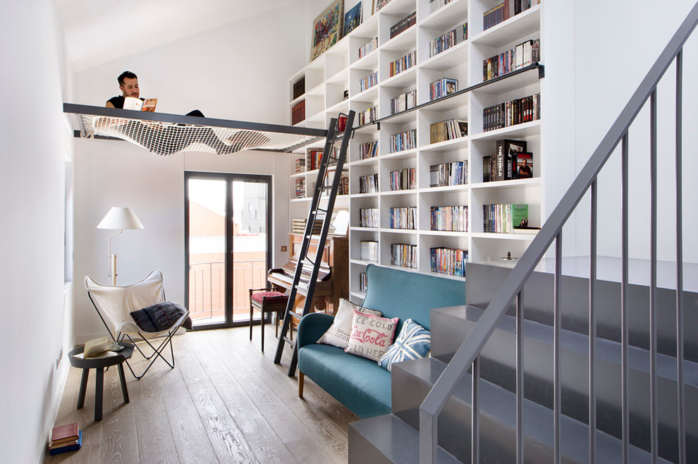 Foto di un piccolo soggiorno contemporaneo aperto con libreria, pareti bianche, pavimento in legno massello medio, nessun camino e nessuna TV