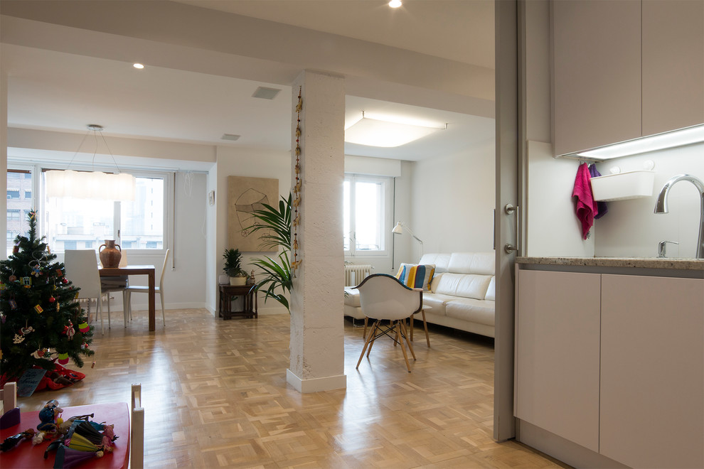 Modelo de sala de estar abierta actual de tamaño medio sin televisor con paredes blancas y suelo de madera clara