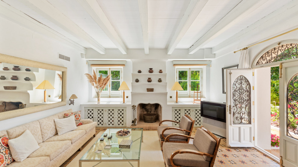 Imagen de sala de estar mediterránea con paredes blancas, suelo multicolor y vigas vistas