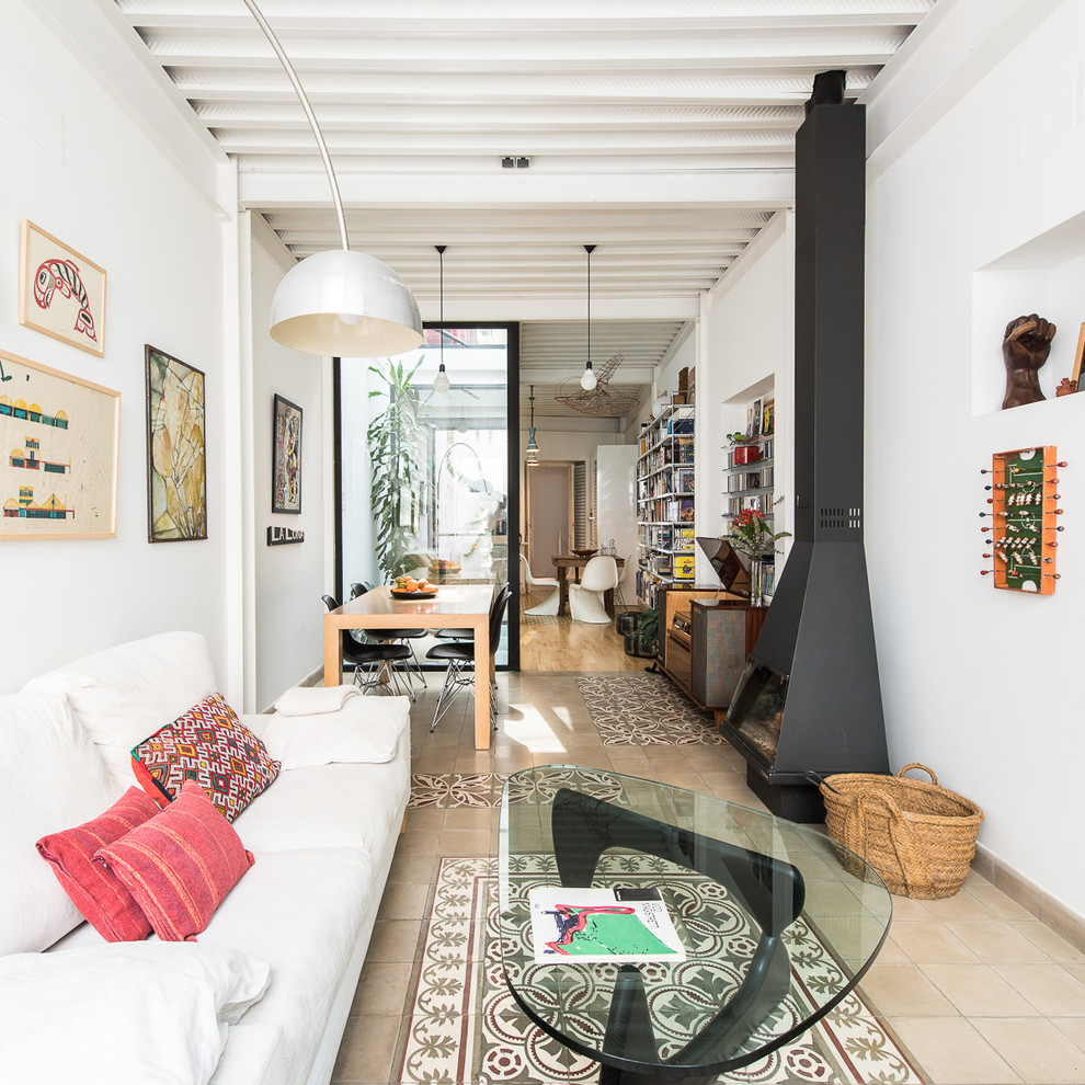 Large bohemian open plan games room in Seville with white walls, ceramic flooring, a wood burning stove, beige floors and a metal fireplace surround.