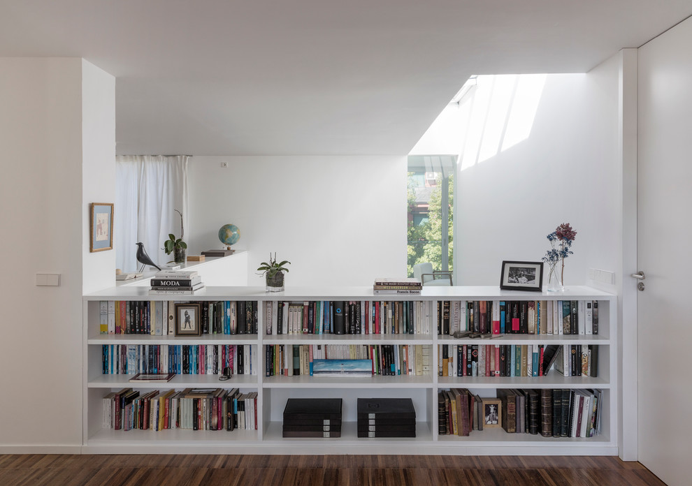 Immagine di un grande soggiorno contemporaneo aperto con libreria, pareti bianche, pavimento in legno massello medio e pavimento marrone