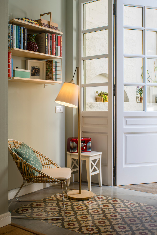 На фото: открытая гостиная комната среднего размера в скандинавском стиле с с книжными шкафами и полками, белыми стенами, полом из керамической плитки и разноцветным полом без камина, телевизора