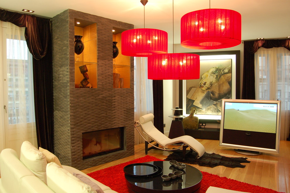 Imagen de sala de estar cerrada actual de tamaño medio con paredes beige, suelo de madera clara, chimenea lineal, televisor independiente y marco de chimenea de metal