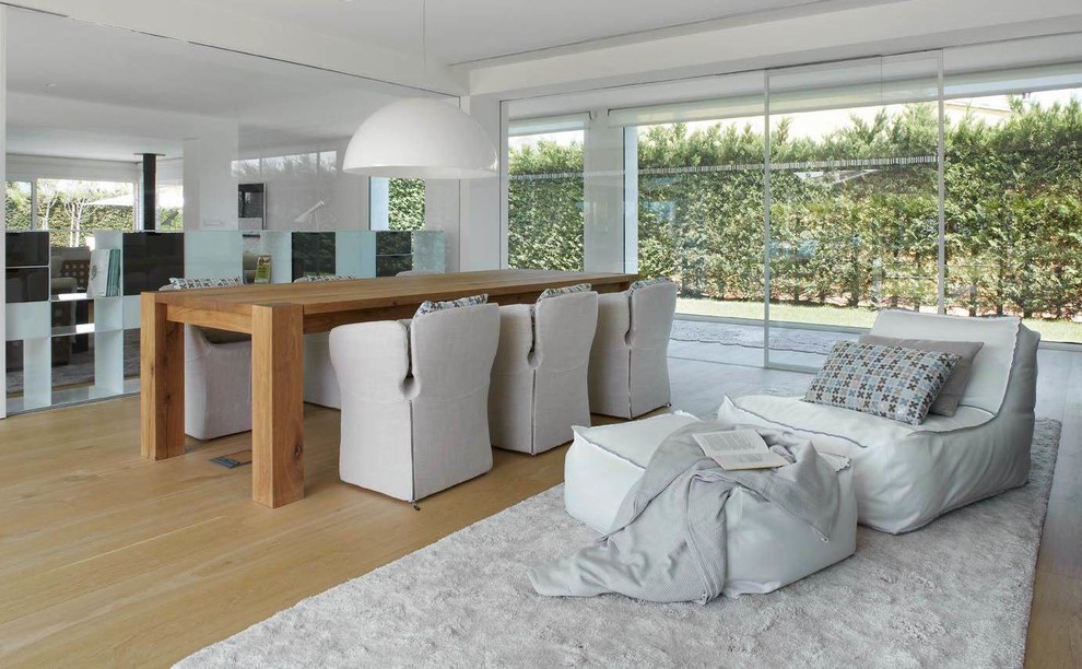 Ejemplo de sala de estar abierta contemporánea de tamaño medio sin chimenea y televisor con paredes blancas y suelo de madera en tonos medios