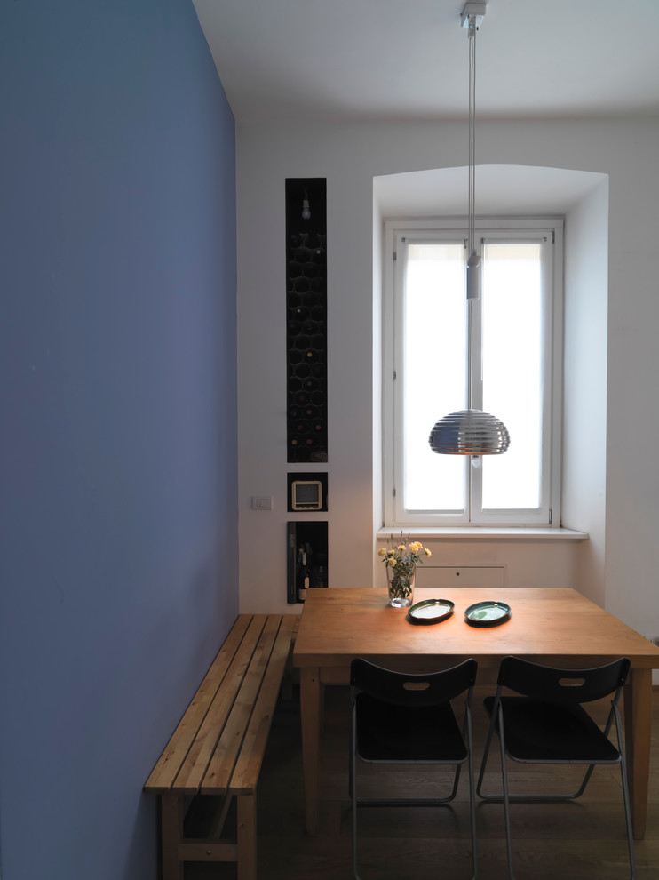 Ispirazione per una piccola sala da pranzo aperta verso la cucina minimal con pareti blu, parquet chiaro, camino bifacciale e pavimento beige