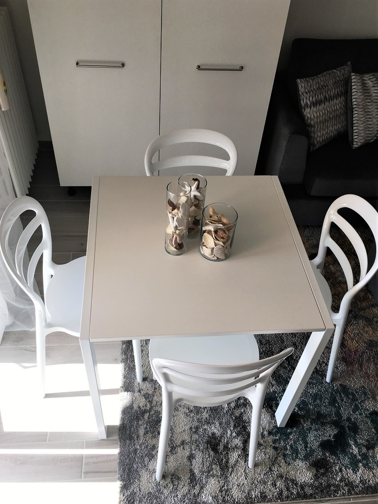 Esempio di una piccola sala da pranzo aperta verso la cucina design con pareti bianche, pavimento in gres porcellanato e pavimento beige