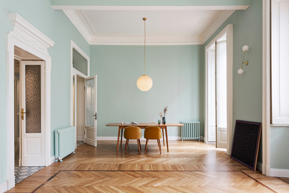 Imagen de comedor actual con paredes verdes, suelo de madera clara y suelo beige