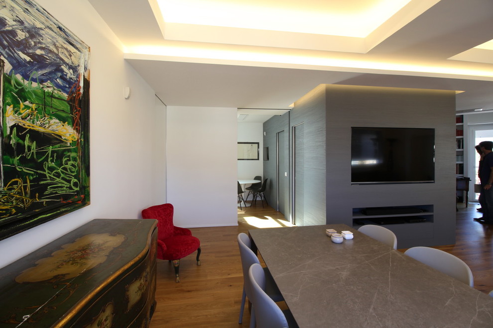 Example of a mid-sized trendy light wood floor and brown floor dining room design in Catania-Palermo with gray walls, a corner fireplace and a plaster fireplace