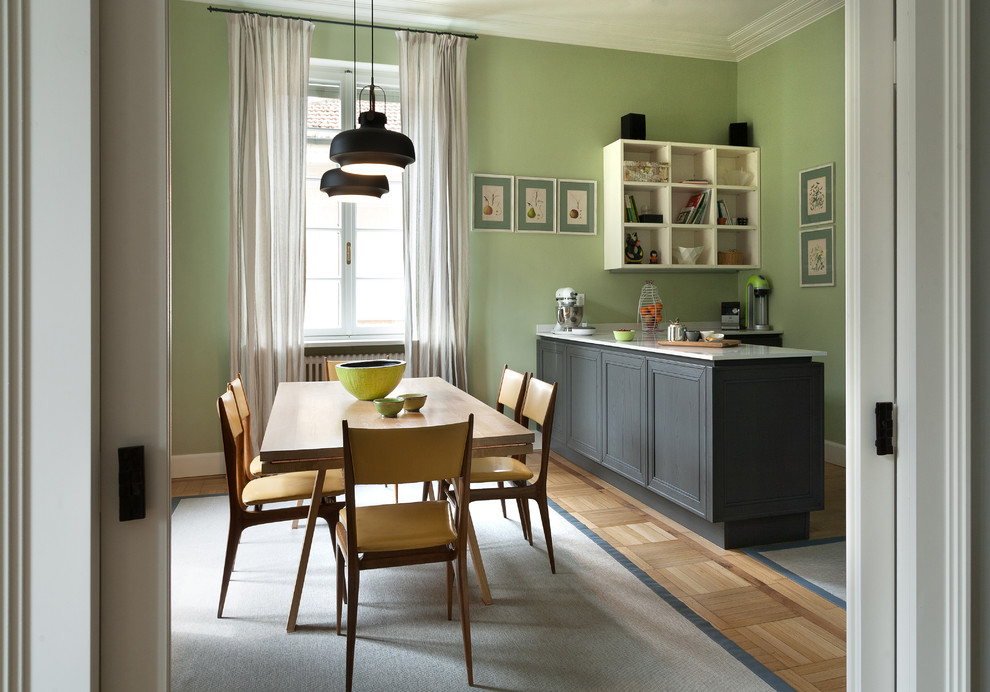 Cette photo montre une grande salle à manger éclectique avec un mur vert et parquet clair.