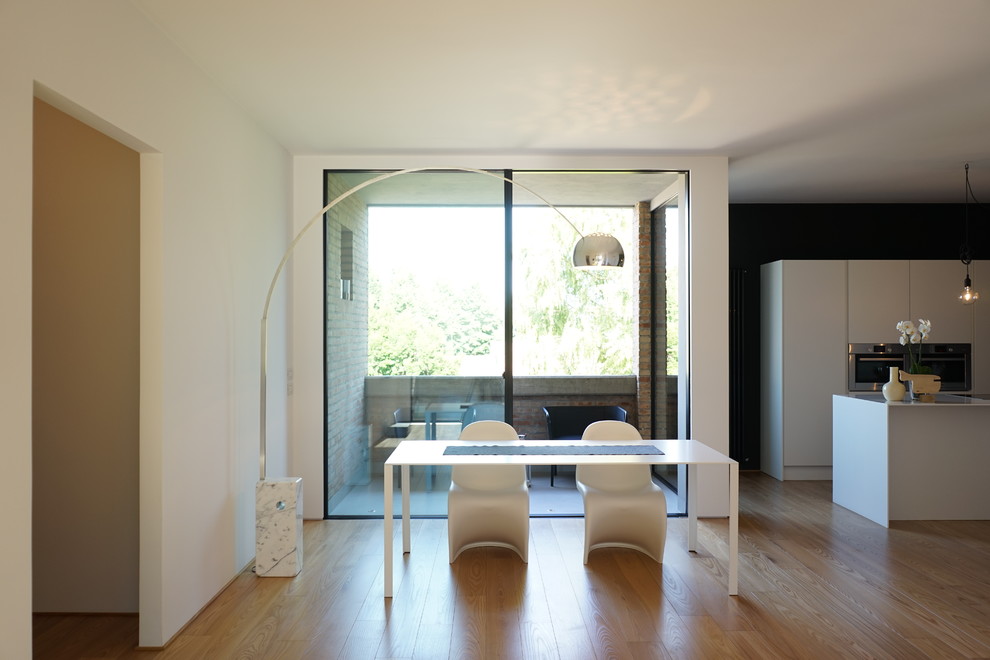 Immagine di una grande sala da pranzo aperta verso il soggiorno moderna con pareti bianche e pavimento in legno massello medio