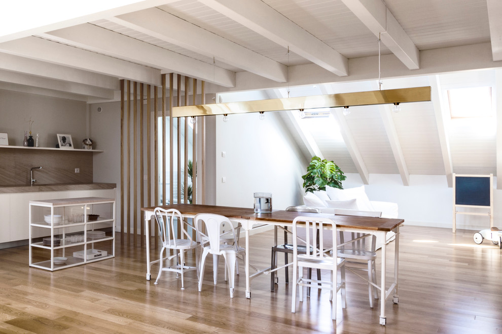 This is an example of a contemporary kitchen/dining room in Milan with white walls and dark hardwood flooring.