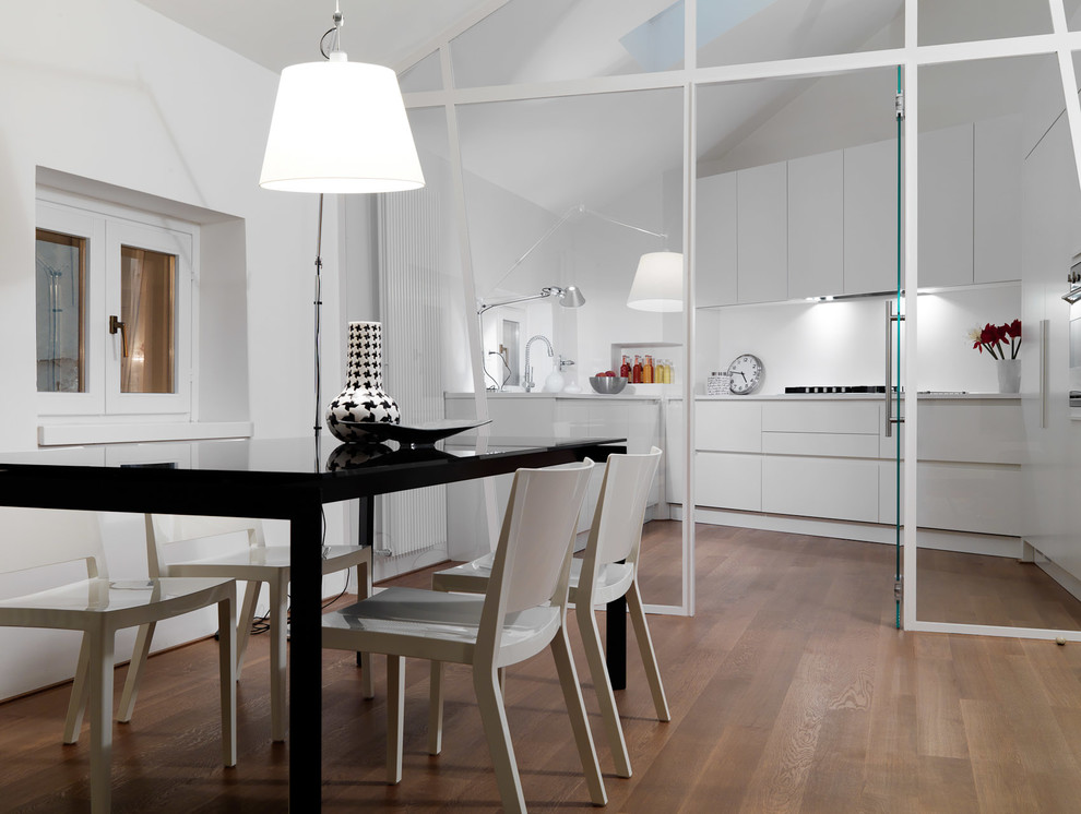 Foto di una sala da pranzo aperta verso la cucina contemporanea con pareti bianche e parquet chiaro