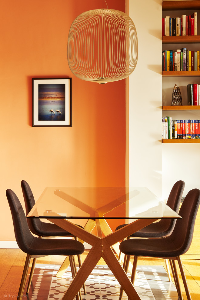 Aménagement d'une petite salle à manger ouverte sur le salon moderne avec un mur orange, parquet foncé et un sol marron.