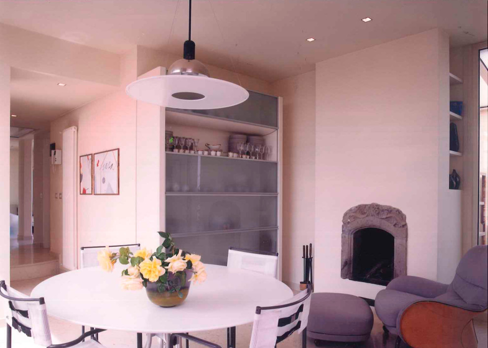 Immagine di una sala da pranzo minimalista di medie dimensioni con pavimento in marmo, camino classico e cornice del camino in pietra