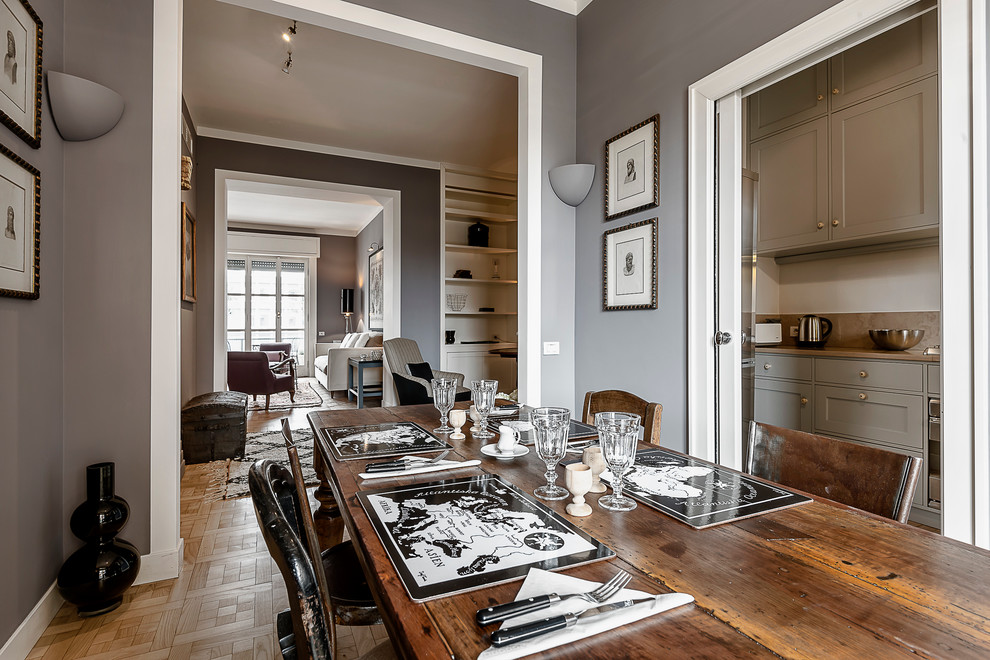 Inspiration for an eclectic dining room in Milan with grey walls, medium hardwood flooring and a plastered fireplace surround.