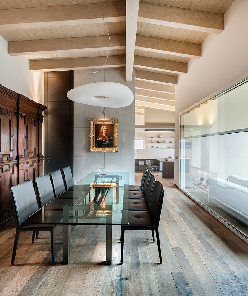 Photo of a contemporary dining room in Milan with light hardwood flooring.