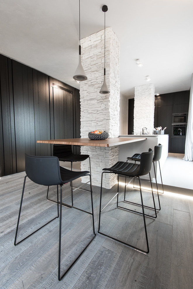This is an example of a medium sized contemporary dining room in Milan with white walls, light hardwood flooring and grey floors.