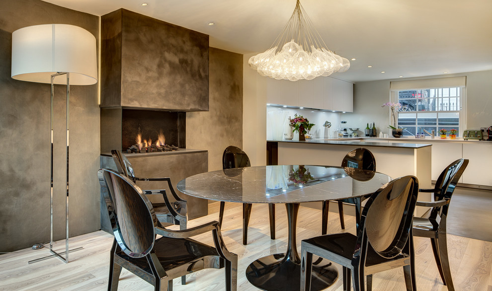 Aménagement d'une salle à manger ouverte sur la cuisine contemporaine avec un mur gris, une cheminée ribbon et un manteau de cheminée en béton.