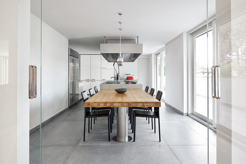Foto di una sala da pranzo aperta verso la cucina contemporanea con pareti bianche e pavimento grigio