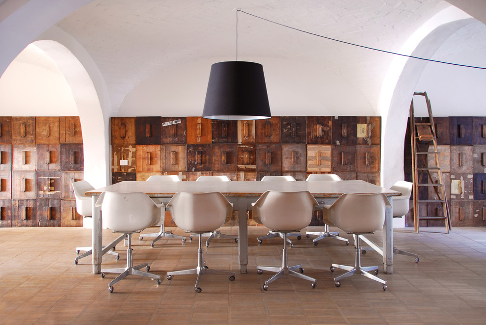 Immagine di una grande sala da pranzo industriale con pareti bianche e pavimento in legno massello medio