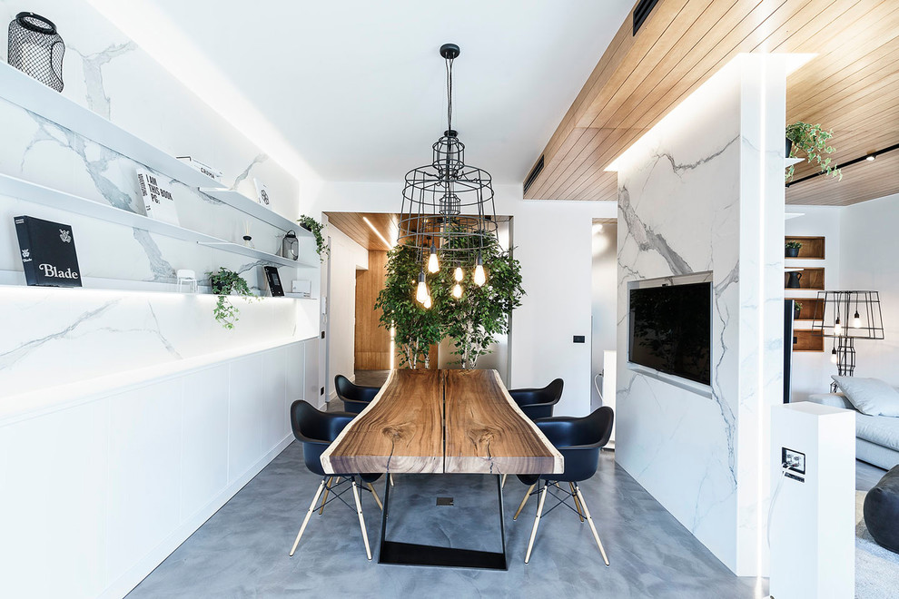 Cette photo montre une salle à manger ouverte sur le salon tendance de taille moyenne avec un mur blanc, sol en béton ciré, aucune cheminée et un sol gris.