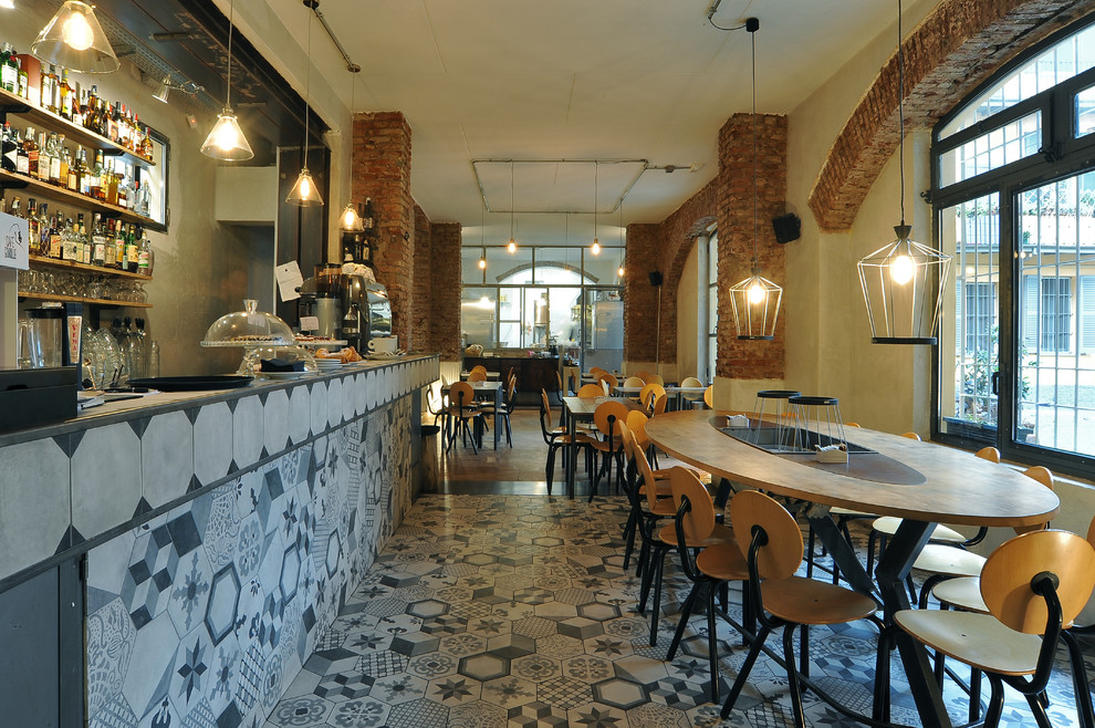 Immagine di una grande sala da pranzo aperta verso la cucina minimalista con pareti arancioni e pavimento in gres porcellanato