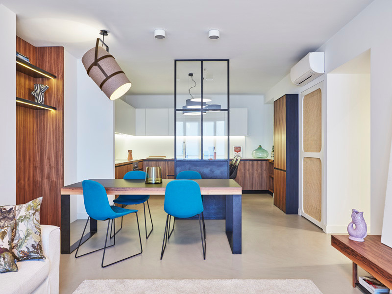Immagine di una sala da pranzo aperta verso la cucina moderna di medie dimensioni con pareti bianche, pavimento in cemento, nessun camino e pavimento grigio