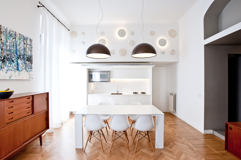 Réalisation d'une salle à manger ouverte sur la cuisine design avec un mur blanc et un sol en bois brun.