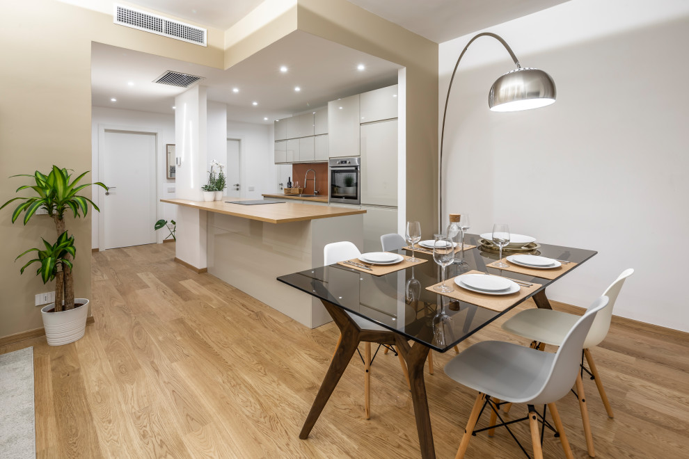 This is an example of a medium sized contemporary kitchen/dining room in Milan with white walls, medium hardwood flooring and beige floors.