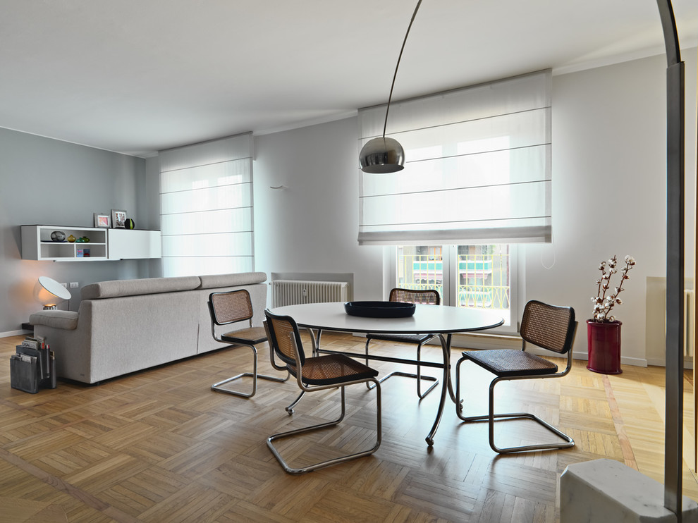 Idee per una sala da pranzo moderna di medie dimensioni con pareti grigie, parquet chiaro e pavimento marrone