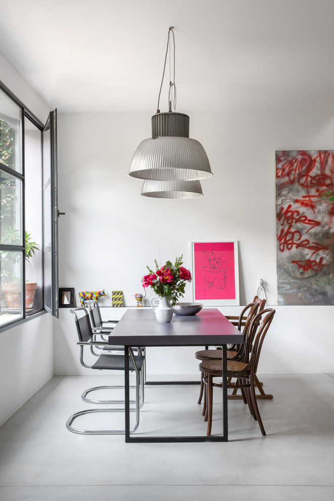 Dining room - industrial concrete floor and gray floor dining room idea in Milan with white walls