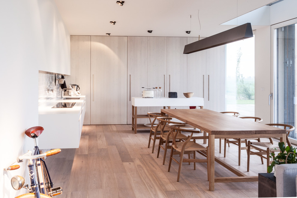 Large scandi kitchen/dining room in Milan with white walls and light hardwood flooring.
