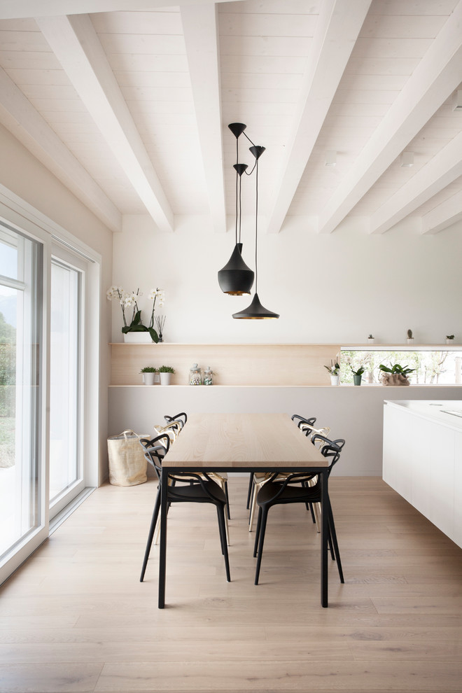 На фото: столовая в скандинавском стиле с белыми стенами, светлым паркетным полом и бежевым полом с
