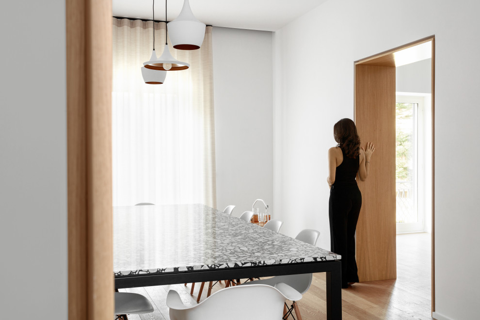 Immagine di una sala da pranzo aperta verso la cucina nordica con pareti bianche e parquet chiaro