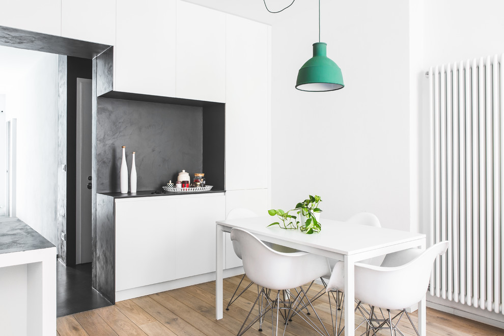 Small contemporary open plan dining room in Bologna with white walls, light hardwood flooring and brown floors.