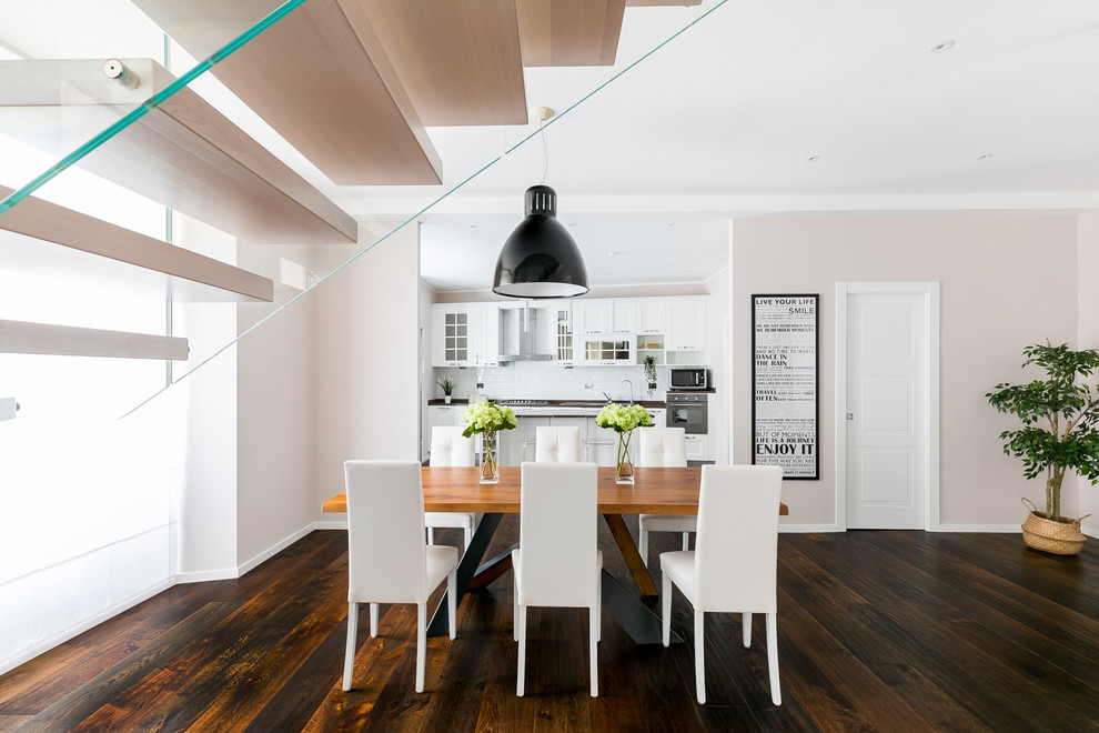 Immagine di una sala da pranzo aperta verso il soggiorno contemporanea con pareti beige, parquet scuro e pavimento marrone