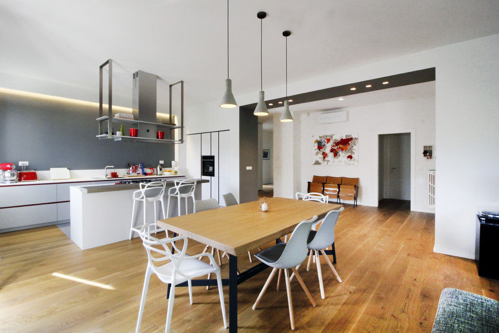 Esempio di una grande sala da pranzo aperta verso il soggiorno minimal con pareti bianche, pavimento in legno verniciato e pavimento marrone