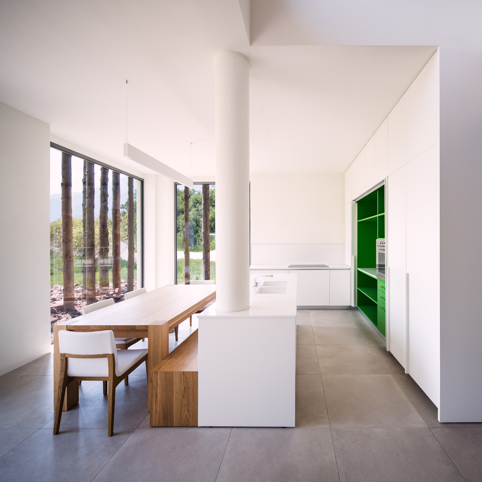 Cette photo montre une très grande salle à manger ouverte sur la cuisine moderne avec un mur blanc, un sol en carrelage de porcelaine et un sol gris.