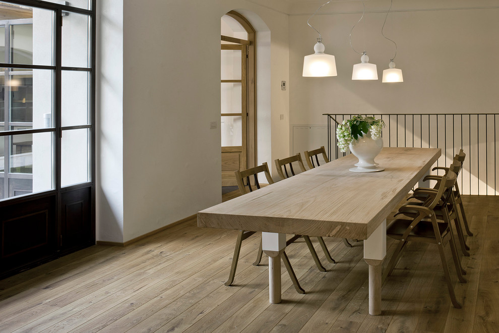 Immagine di una sala da pranzo industriale con pareti bianche e parquet chiaro