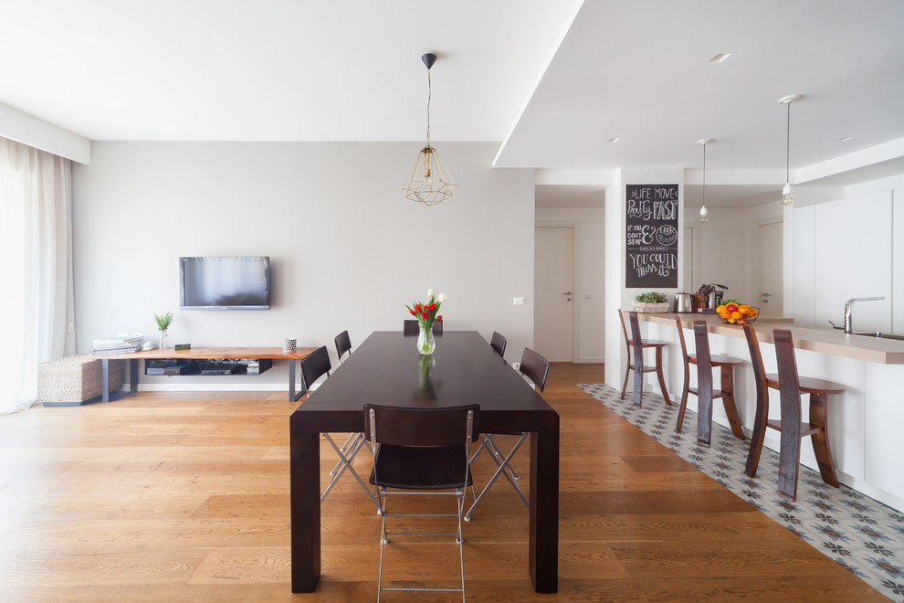 Foto di una grande sala da pranzo aperta verso la cucina minimal con pareti grigie e pavimento in legno massello medio
