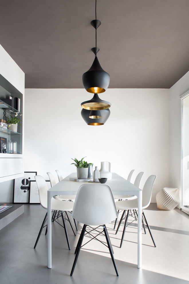 This is an example of a scandinavian dining room in Milan with white walls and grey floors.