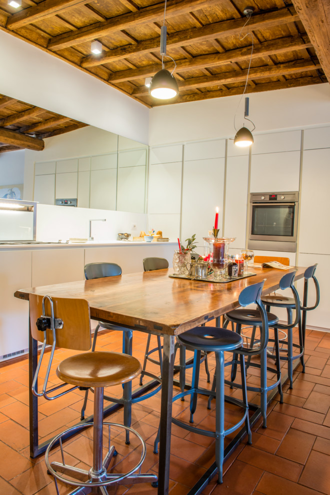 Immagine di una grande sala da pranzo aperta verso la cucina boho chic con pavimento rosso, pareti bianche e pavimento in mattoni