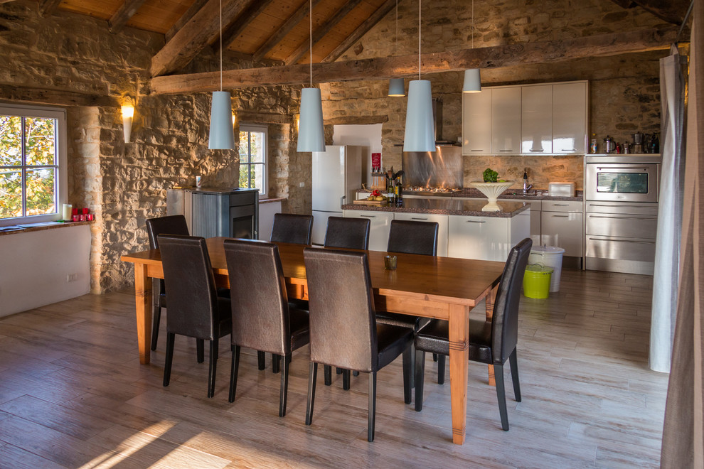 Cette image montre une grande salle à manger ouverte sur la cuisine minimaliste avec un sol en bois brun, un mur multicolore et un sol beige.
