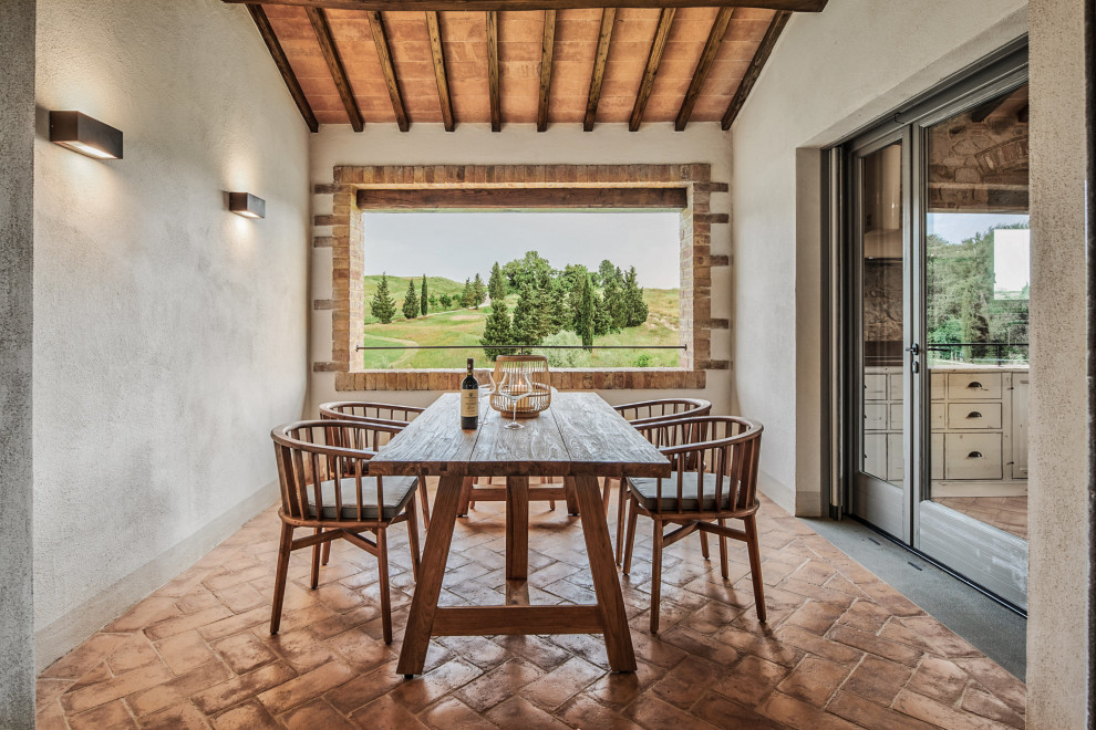Ispirazione per una sala da pranzo mediterranea di medie dimensioni con pareti beige, pavimento in terracotta, pavimento marrone e soffitto in legno
