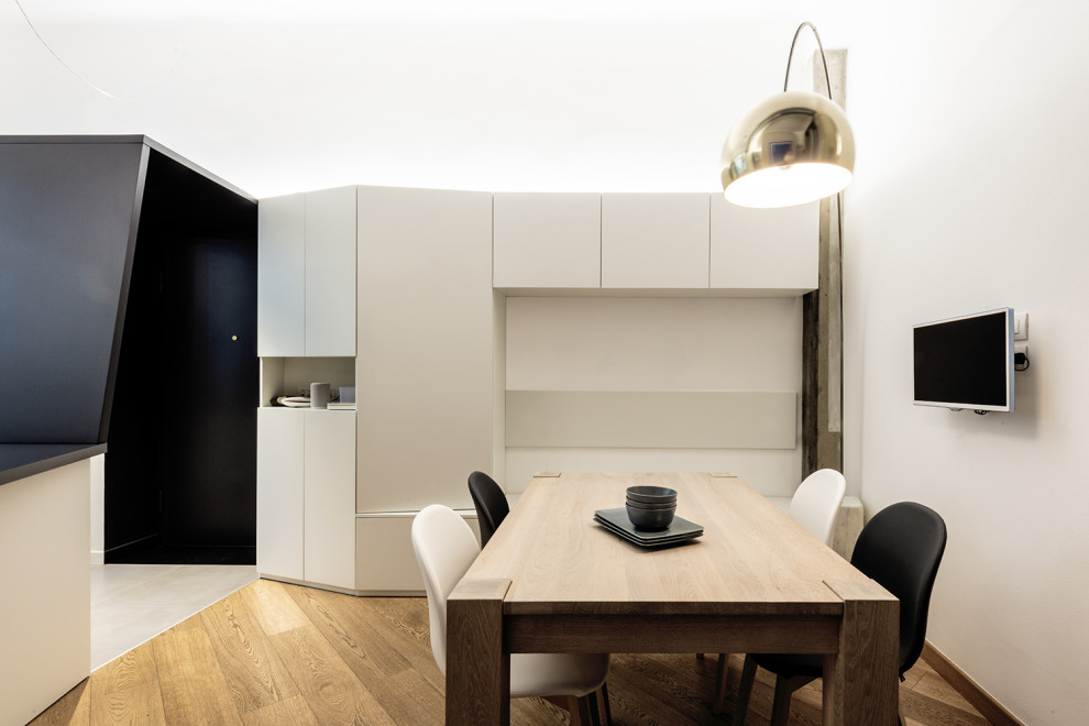 This is an example of a small contemporary kitchen/dining room in Milan with white walls, light hardwood flooring and beige floors.