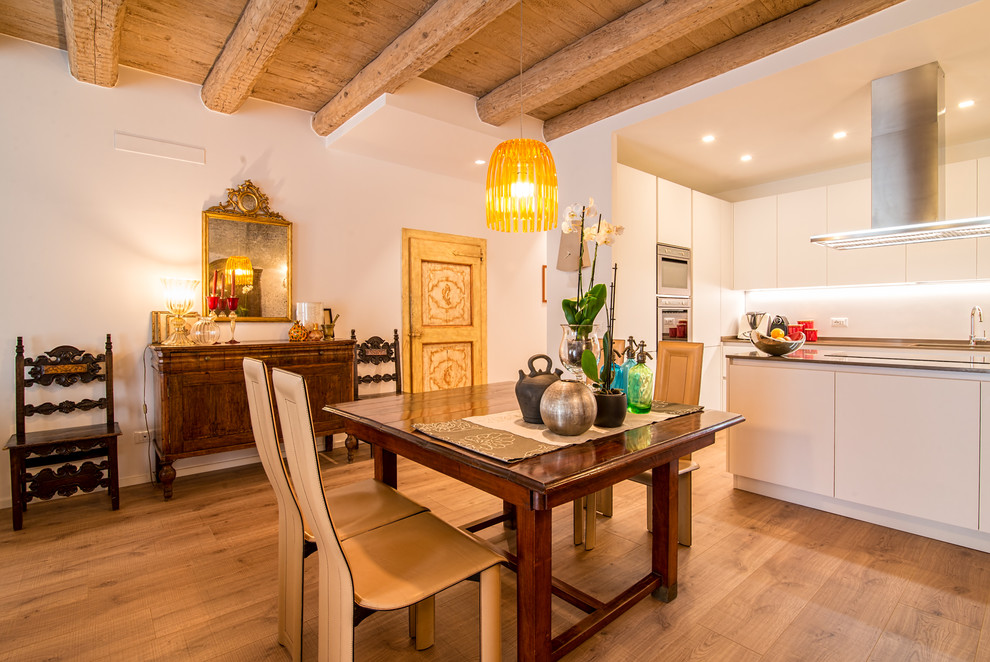Foto di una sala da pranzo aperta verso la cucina bohémian con pareti bianche, parquet chiaro e pavimento marrone