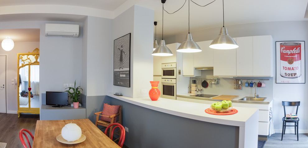 Foto di una sala da pranzo aperta verso la cucina moderna di medie dimensioni con pareti bianche, pavimento in laminato e pavimento grigio
