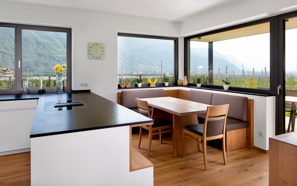 Cette photo montre une salle à manger ouverte sur la cuisine tendance de taille moyenne avec un sol en bois brun, un mur blanc et un sol beige.